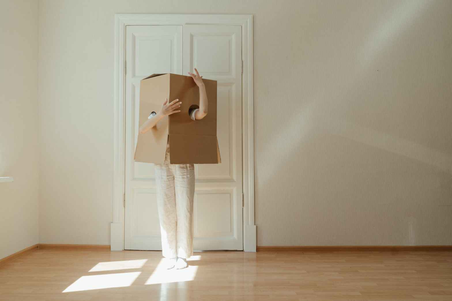 woman in white long sleeve shirt and white pants standing on brown wooden floor